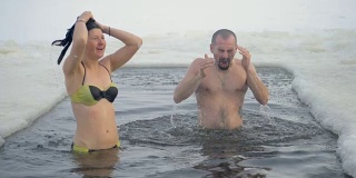 一个穿着泳衣的男人和一个女人在冰洞里。
