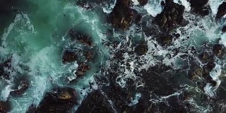 海浪撞击着黑色的岩石-鸟瞰图
