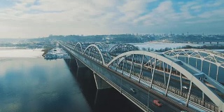 汽车和火车在结冰的河流上的一座桥上移动