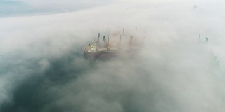 在保加利亚瓦尔纳海港，无人机拍摄的大雾中的货船和工业起重机