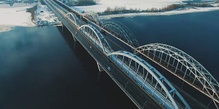 汽车和火车在结冰的河流上的一座桥上移动