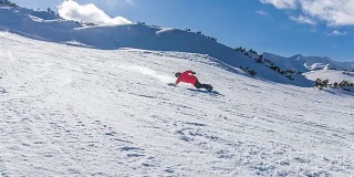 在一个阳光明媚的日子里，滑雪者从滑雪坡上滑下来，将雪喷向摄像机