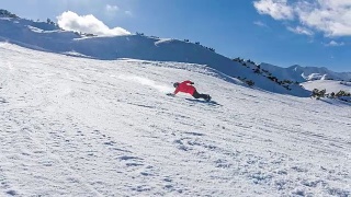 在一个阳光明媚的日子里，滑雪者从滑雪坡上滑下来，将雪喷向摄像机视频素材模板下载