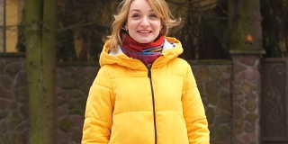 30-40岁的美女真诚地笑。她穿着一件亮黄色的夹克，戴着一条红色的围巾