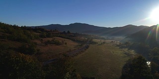 空中秋日的日出景色以黄色落叶松、小村庄和奥德尔盖斯勒山群为背景。意大利白云石阿尔卑斯山脉