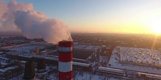 空中特写的一个巨大的冷却塔与白色的烟雾在冬季日落