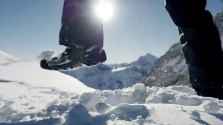 慢镜头拍摄的人走在雪山环境在阳光明媚的一天视频素材模板下载