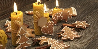 圣诞节自制的姜饼曲奇放在木桌上。由天然蜂蜡制成的黄色香味蜡烛。