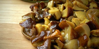 腌蘑菇片在木制的背景。玻璃罐内的香菇。