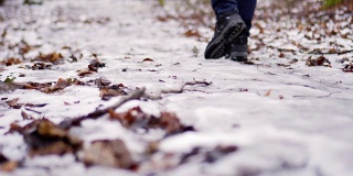 穿冬靴的腿穿过厚厚的积雪。近距离观察鞋子。在雪滩上行走，在冬天徒步旅行。