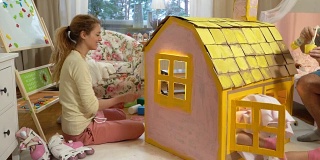 年轻的家庭和孩子一起建造和油漆玩具纸板房子