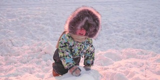一个小孩在冬季公园玩。一个晴朗的冬日。新鲜的空气里充满了乐趣和游戏。
