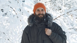 一名男子在一个冬日下雪天的户外对着镜头微笑和挥手视频素材模板下载