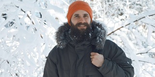 一名男子在一个冬日下雪天的户外对着镜头微笑和挥手