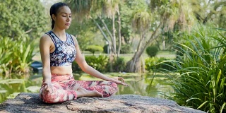 瑜伽在公园，年轻的亚洲女子在姿势坐莲花位置和冥想