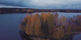 在秋天的森林中，在蓝色的湖上有一个黄色的树木繁茂的岛屿