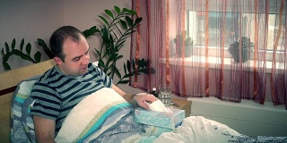 生病的男人躺在家里的床上擦鼻涕。季节过敏恶化
