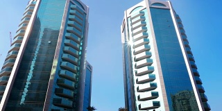 在沙迦现代城市的现代摩天大楼的玻璃幕墙反射阳光
