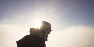 女孩徒步旅行在雪上的斯洛伐克山脉在冬季日落云层之上的慢动作
