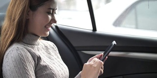 亚洲女性在车里用智能手机进行社交媒体