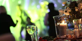 一群剪影的人在一个黑暗的宴会厅跳舞的婚礼招待会。婚宴上，人们跳舞——射婚庆餐桌装饰，婚礼装饰