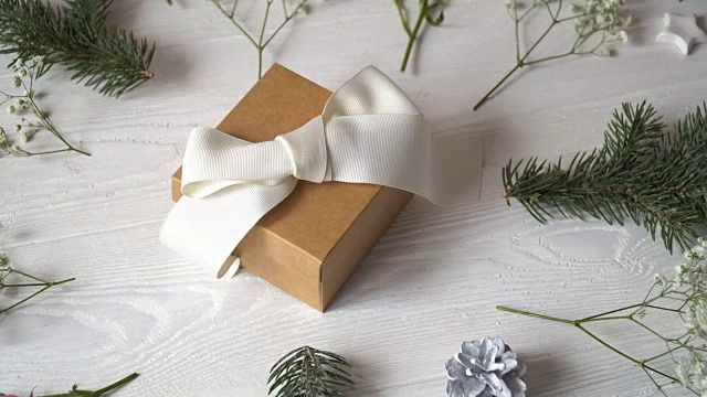 牛皮纸礼物与白色蝴蝶结和鲜花贺卡为情人节或婚礼在乡村风格与地方为你的文字，平躺，俯视图