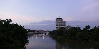 晚上桥上的交通。间隔拍摄黄昏。在泰国清迈河上航行的船只。城市黄昏