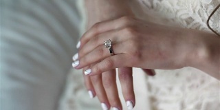 女性双手合上，用银金戒指钻石架聚焦。女人在婚礼前戴上订婚戒指，涂上指甲油，穿上蕾丝礼服。人生富有魅力财富灰姑娘