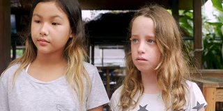 两个无聊的年轻女孩站在一起看着镜头