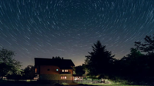 星迹时间流逝在房子上方，彗星模式。居民楼和天空中星星的轨迹。