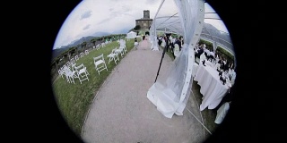 活动婚礼摄影师拍摄视频在接待宴会室外使用圆形鱼眼镜头检查设备搜索照片拍摄脚下在城堡草草坪椅子桌子安排的背景