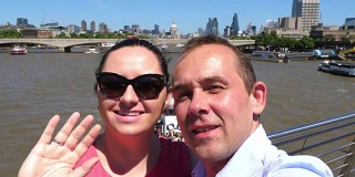 一对夫妇在用4k慢镜头拍摄泰晤士河和伦敦碎片大厦的自拍照