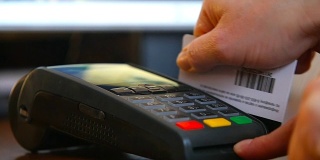 女性手拿银行卡使用终端机进行支付。非现金支付的概念