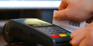 女性手拿银行卡使用终端机进行支付。非现金支付的概念