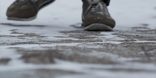 男性的腿在冬天的鞋子走在雪地上的特写。镜头，在冬天穿着雪鞋和钉鞋在雪地上行走的景象。穿靴子的男人们的腿挡住了白雪覆盖的小路