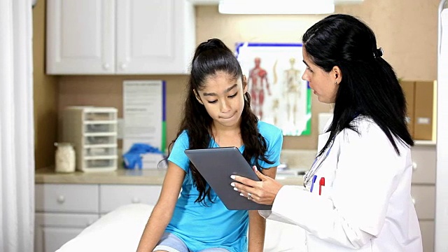 拉丁女医生拿着数字平板电脑。她正在给年轻的拉丁女病人做体育检查。
