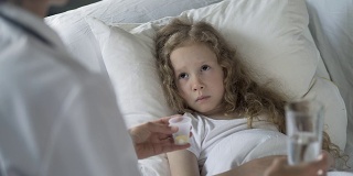 护士给免疫系统低下、流感流行的不开心孩子吃药