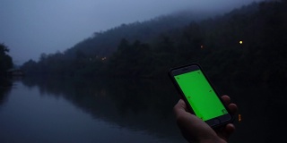 男子在河边使用手机绿屏