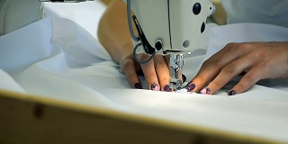 一个专业的裁缝在服装厂完成一个订单缝制时髦的衣服的特写。