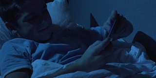兴奋的青少年晚上躺在床上玩手机游戏，自律