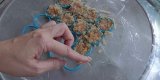 女用手把拌有西瓜汁的米放在模具里做成炒年糕。米饼是泰国的传统小吃。