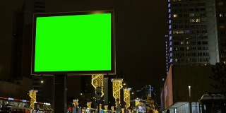 街道上有一块绿色屏幕的大广告牌为节日装饰。