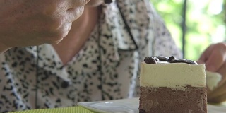 老人在咖啡厅吃巧克力慕斯蛋糕。亚洲老妇人坐在餐厅品尝美味的甜点。