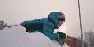 一个少年在雪山上玩耍。从上往下看。阳光明媚的一天。新鲜的空气里充满了乐趣和游戏。