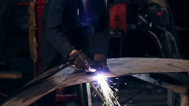 不可辨认的工人都配备了防护服，用工业切割炬用木板来调整金属片。