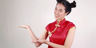 妇女穿着红色旗袍，用手势表示祝贺，寓意春节快乐