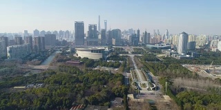 在阳光明媚的一天，绿色公园和上海市中心。中国鸟瞰图。无人机是向前和向上飞行。远景。
