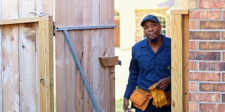 非裔美国蓝领工人带着准备工作的工具穿过后院大门