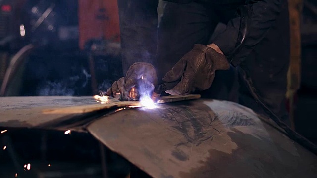 穿着防护服的男工人正在用氧乙炔切割炬切割金属构件