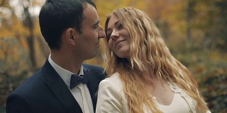 一对年轻美丽的新婚夫妇一起站在秋天的森林里。结婚的那一天。慢动作